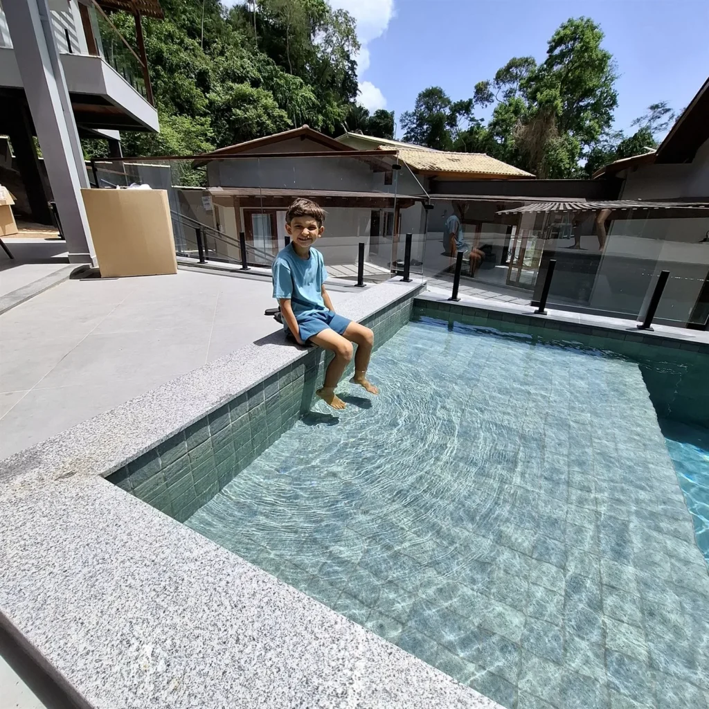 Criança sentada na borda da piscina da Pousada Reale em Paraty
