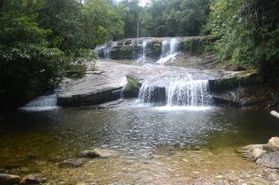 Cachoeira do Iriri, com quedas d'água sobre as pedras e poço cercado de mata atlântica, em Paraty
