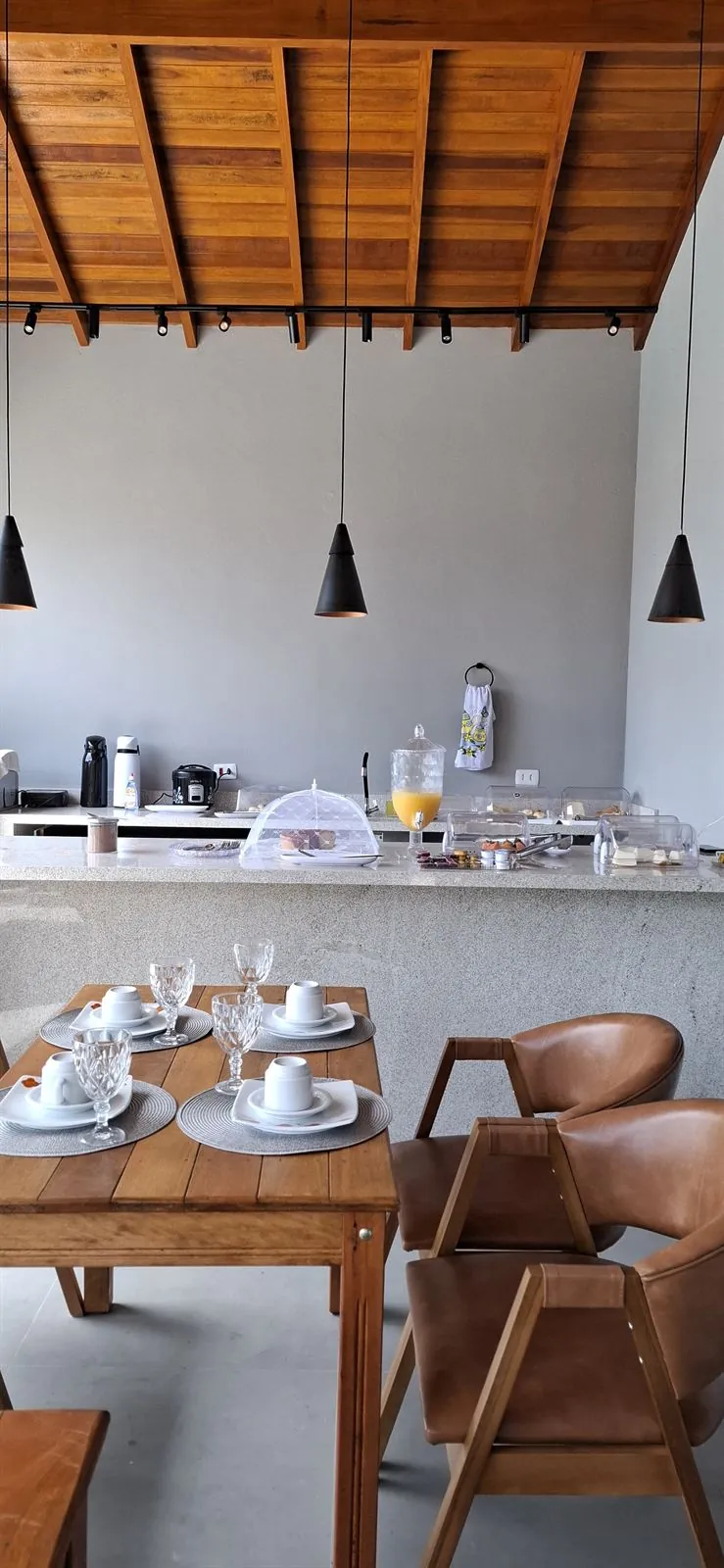 Salão do café com pergolado de madeira e cadeiras em couro