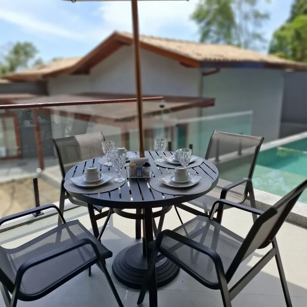 Mesa na varanda com vista para a piscina da pousada